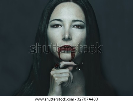 Dark portrait of beautiful young woman with vampire halloween make-up. Halloween or horror theme