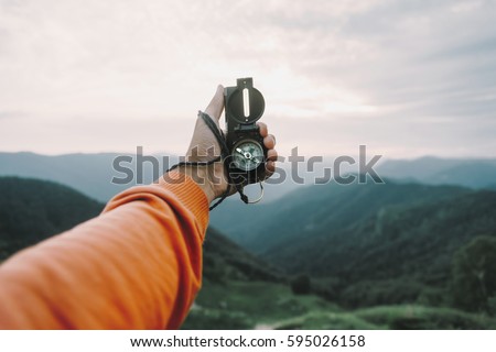Man explorer searching direction with compass in summer mountains, point of view.