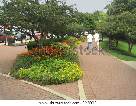 women walking on brick pathway in flower filled park