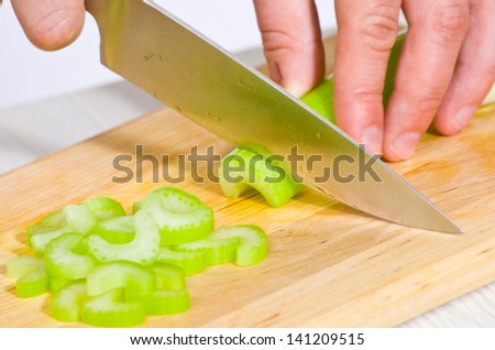 Chef cutting the celery on a wooden board