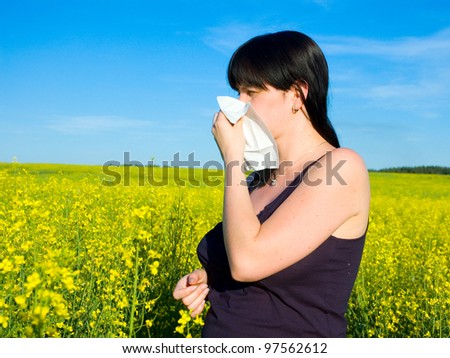 Allergy / Young woman blowing her nose on the rapeseed field