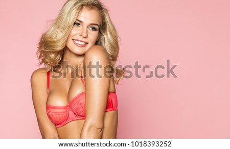 Portrait of a beautiful blond woman in pink lace underwear on a pink background. A horizontal frame with a girl in a festive romantic mood.
