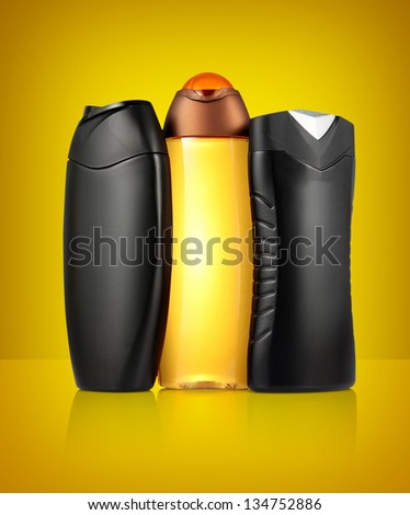 Three different black and orange tubes and bottles for hygiene, health and beauty on a orange background with reflection.