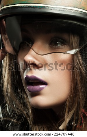 Beautiful young woman with make-up in a motorcycle helmet on a black background closeup