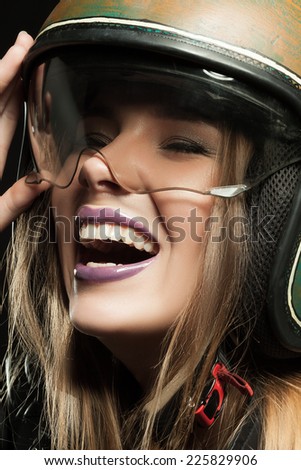 Beautiful young woman with make-up in a motorcycle helmet on a black background close up