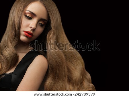 Beautiful girl with long thick shiny hair on a black background. Curly brown hair. Red lipstick
