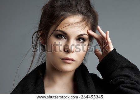 Woman  in black coat with flying locks looking at the camera