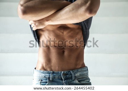 closeup photo sports guy in jeans with perfect abdominal muscles