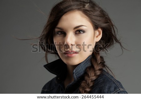 Attractive woman with braided plait in a denim shirt with flying locks
