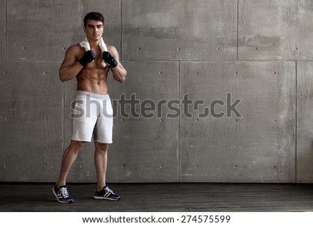 sports guy posing for the camera on the concrete wall background