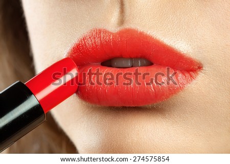 Applying red lipstick on plump lips