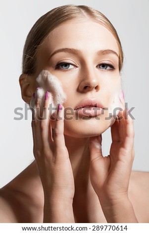 Close-up woman clears skin foam on a gray background