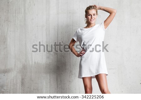 Woman wearing white blank t-shirt  standing on the background of a cement wall