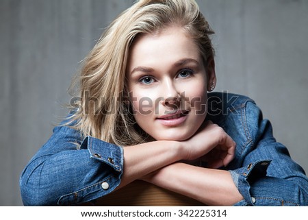 Portrait of a blonde woman with a sweet smile in a denim shirt