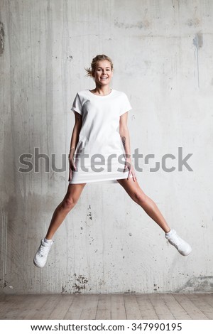 Young woman with a smile wearing a white T-shirt jumps