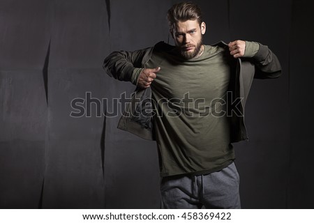 The young man takes off his jacket on gray cement background