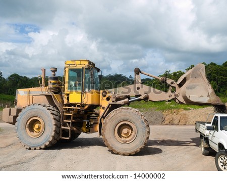 Front end loader loading gravel into a work pick-up vehicle