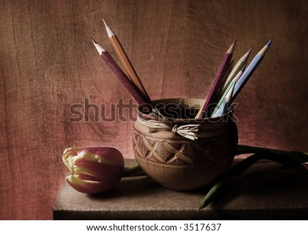 Little jug with tulip and pencils with a brown background, relax feeling