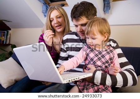 Little girl play with a white laptop with parents