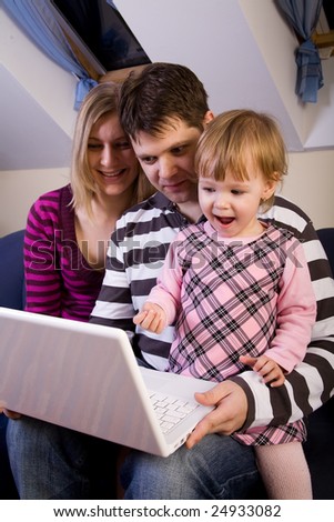 Little girl play with a white laptop with parents