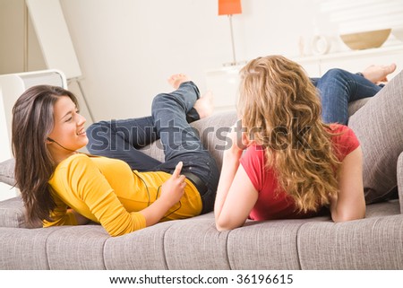 Beautiful blondie brown teenager girls listen music at home on sofa