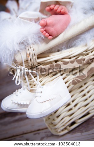 Picture of small baby feet lying on the basket with hanging shoes