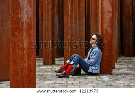 woman sits and waits between rusty columns
