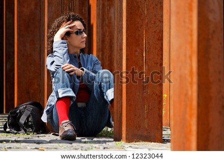 young woman waits to somebody between rusty columns