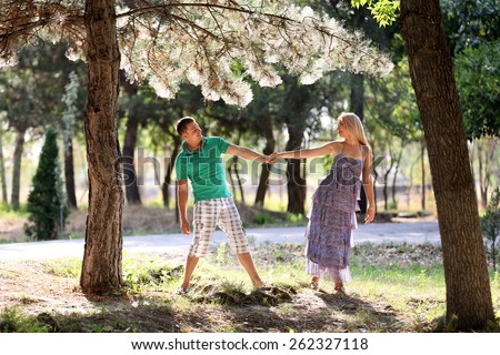 Enamoured guy and the girl walk in wood. Young men, in the summer, in pine wood. A sunny day.