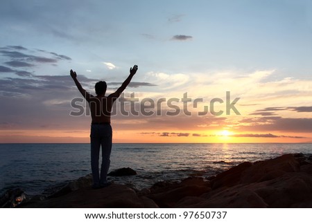 Meeting dawn on  sea.  silhouette of  man. - stock photo