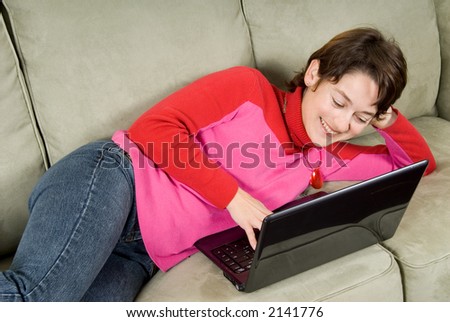 woman smiling on couch with a laptop