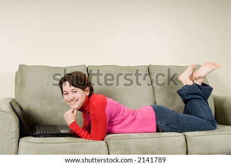 young woman happy on couch with laptop