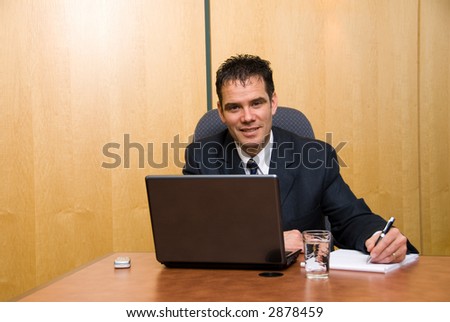 Businessman in a board room with his grey laptop