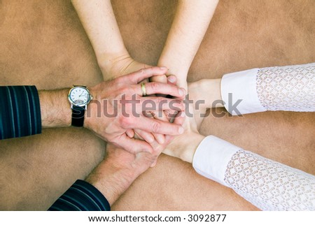six hands clasp together in symbol of unity