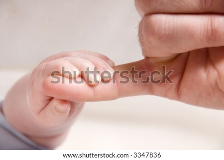 small baby hand holding on to dad\'s finger