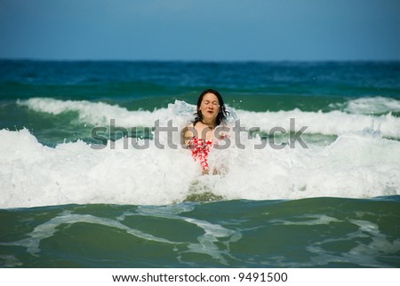 woman playing in the blue wave off the beach