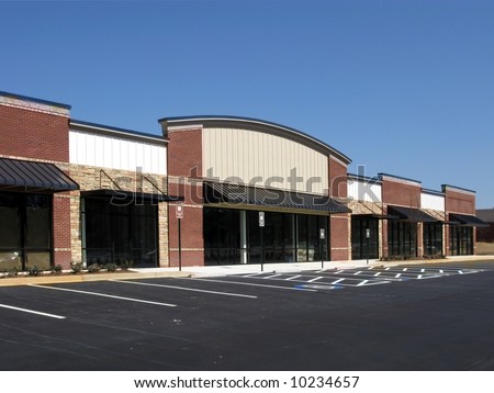 A suburban shopping center made of textured brick, stone, and glass in the final stage of construction.