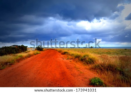 Red road to sea under the cloudy sky
