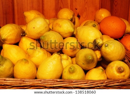 A mound of lemons with a single orange.
