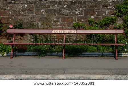 An empty bench on a railway platform marked with the name Goathland