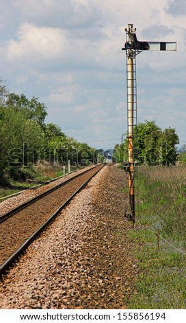 A single track railway line showing the reverse of a Home semaphore signal, the line in the distance is shimmering in the summer heat