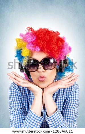 Female with clown wig sending big kiss on blue background