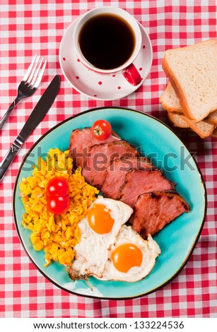 Fried eggs and pork meat on the plate from above