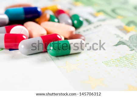 Splashed pills on the money bills. Selective focus on the front green pill