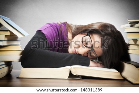 Tired female student sleeping on the big book