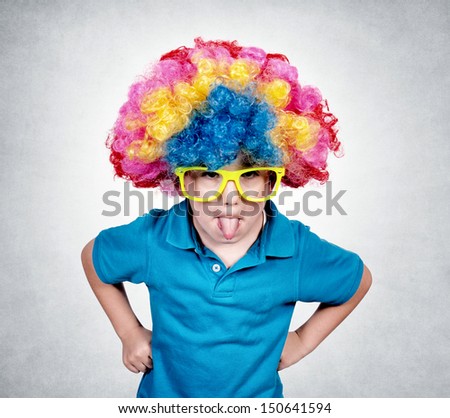 Little boy with clown wig mocking isolated on gray background