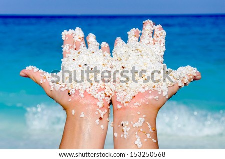 Little white stones in the hand with sea in background
