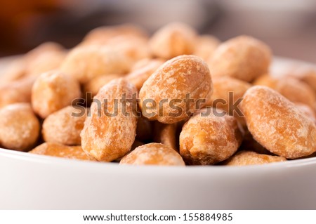 Salted and roasted peanuts in white cup. Selective focus on the front peanuts