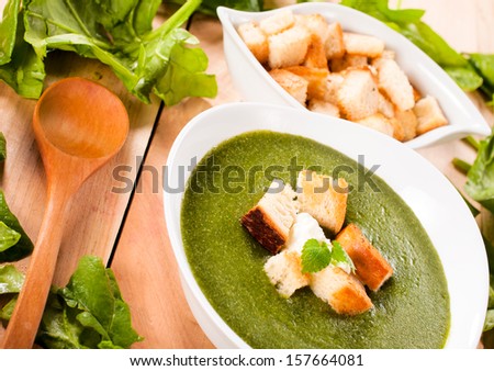 Raw and prepared spinach soup on the wooden table. Selective focus on the spinach soup