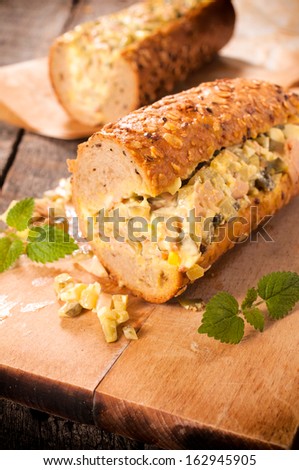 Sub sandwich stuffed with gourmt salad on the wooden board